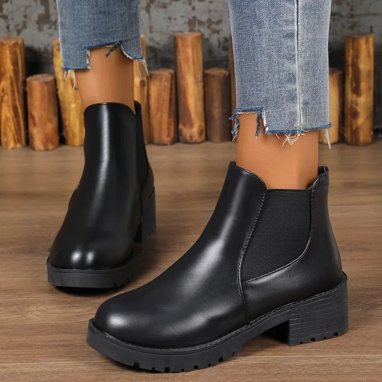 Black Chelsea ankle boots for women with flat chunky heel, round toe, and cloth upper on a light background