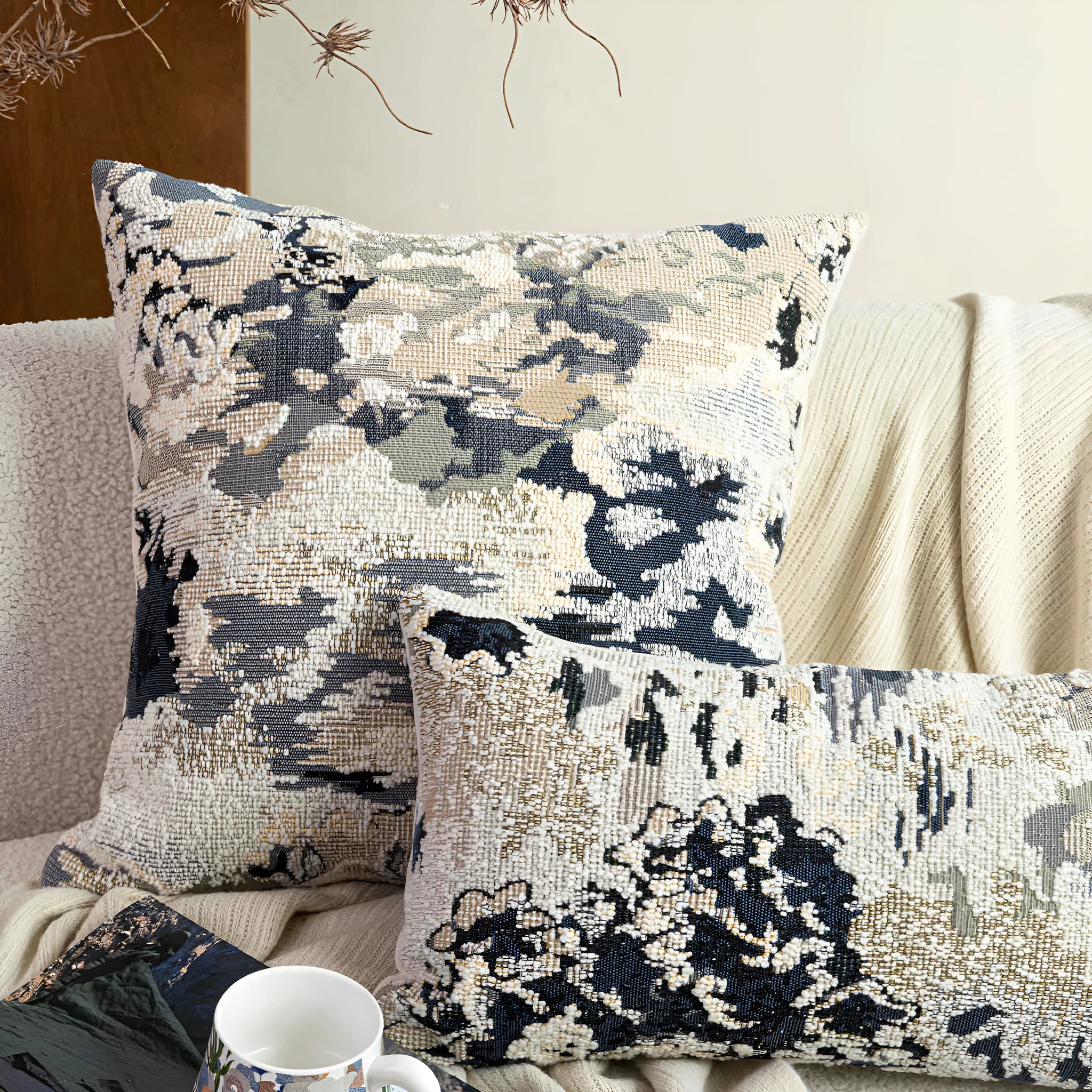 Antique blue abstract floral decorative pillow on a grey sofa, showing square and waist pillow sizes.