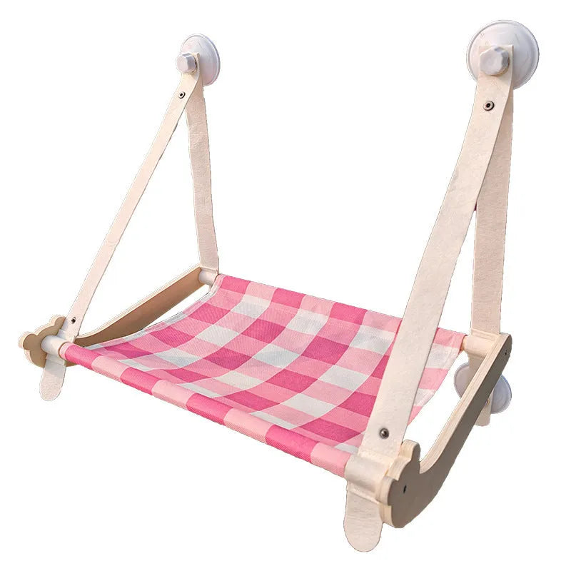 Pink wooden cat hammock bed with suction cups attached to a window