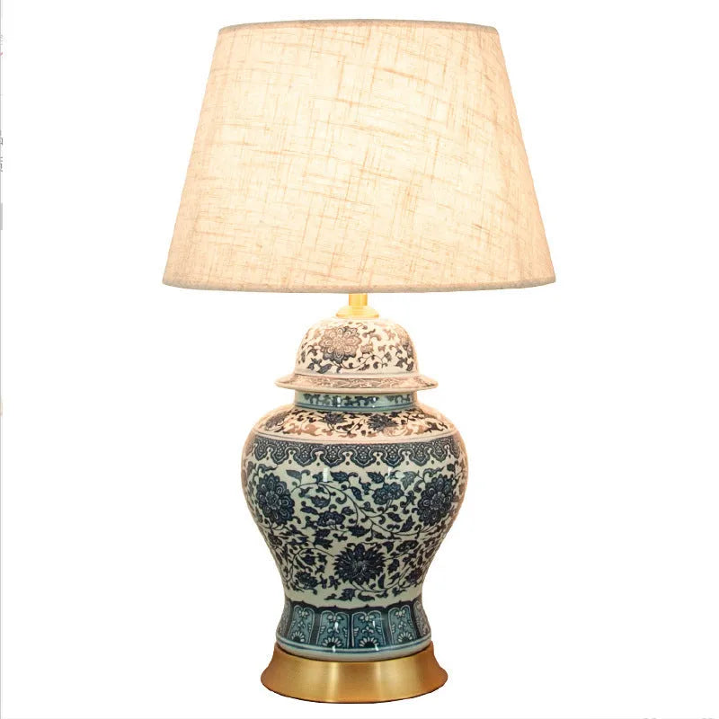 Handmade blue and white porcelain Chinese table lamp with a cloth shade on a wooden surface.