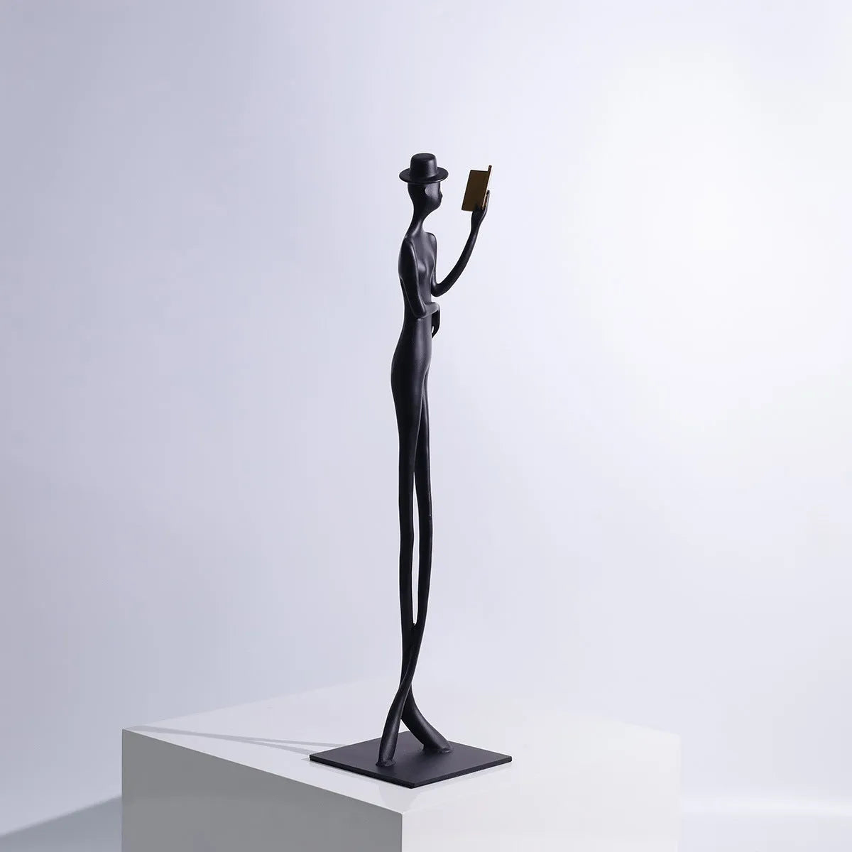 Black cast aluminium sculpture of a woman reading, measuring 51cm tall on a desktop.