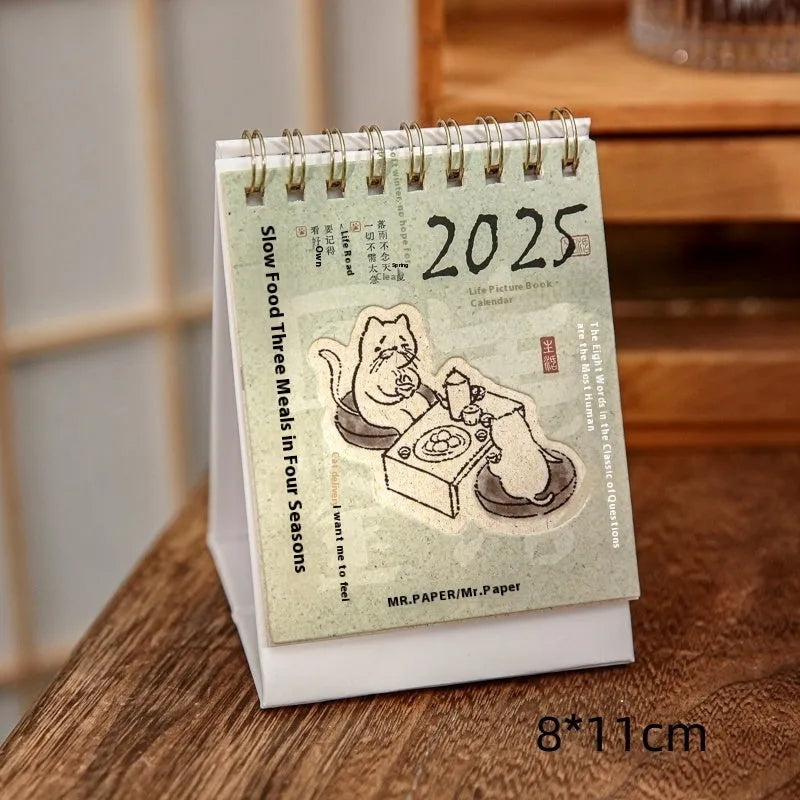 Set of four different 2025 mini paper desk calendars with simple modern designs on a desk.