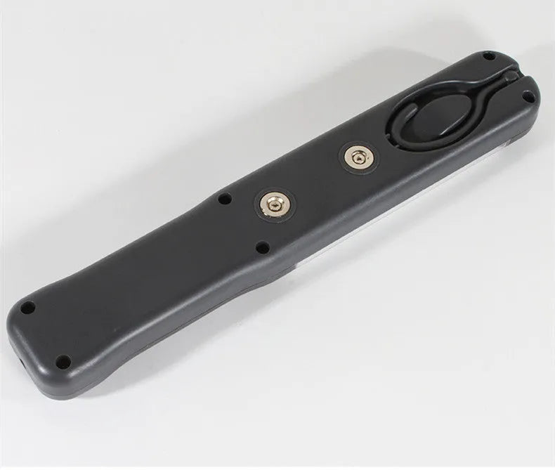 Grey multifunctional LED work light with magnetic base and 360° rotation on a metal surface