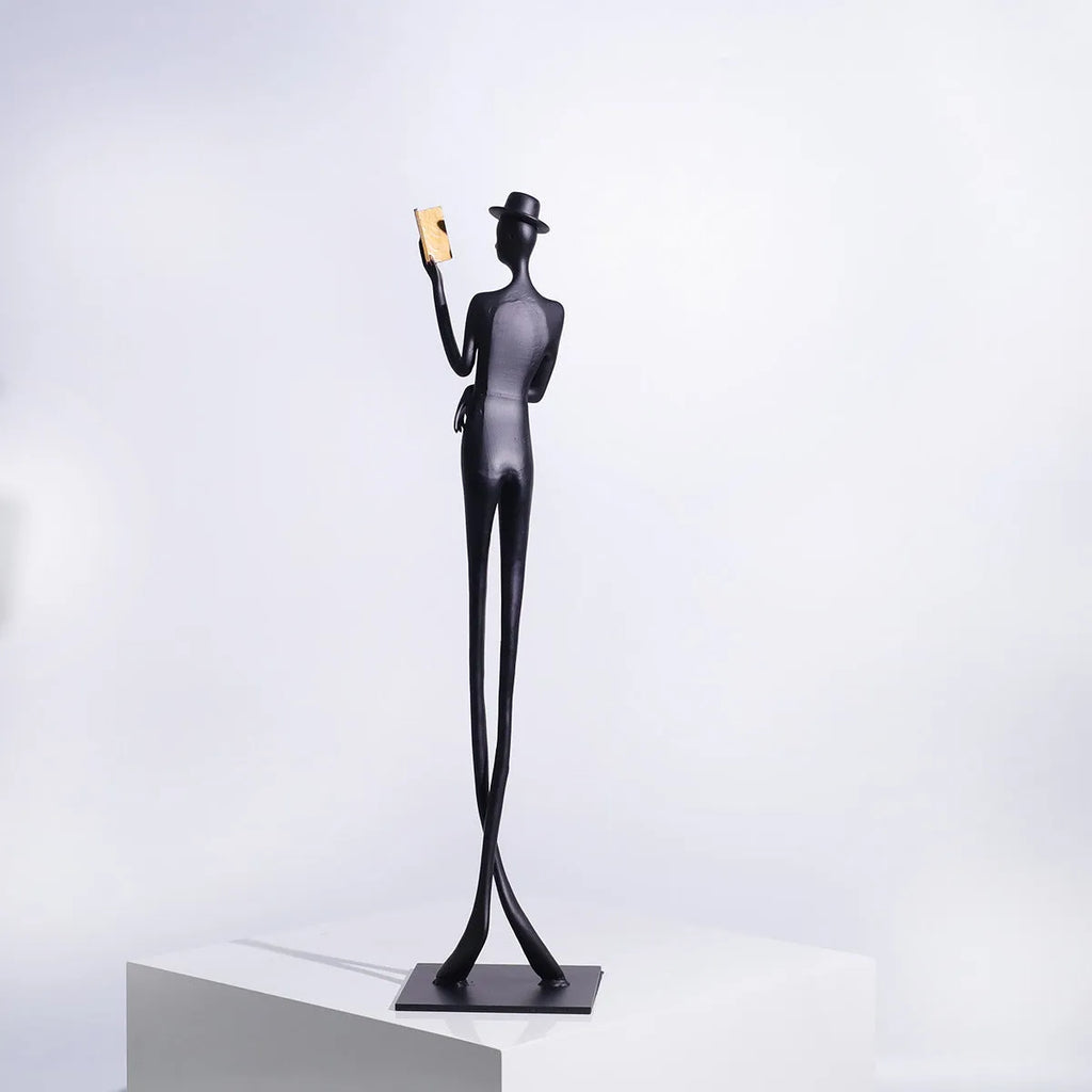 Black cast aluminium sculpture of a woman reading, measuring 51cm tall on a desktop.