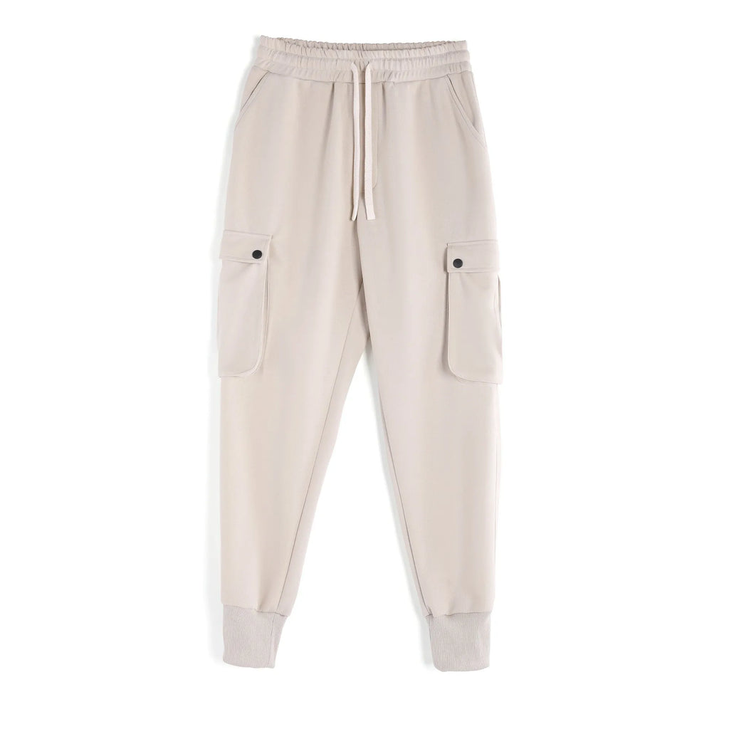 Man wearing loose fit apricot coloured cotton sports trousers with ankle ties and multiple pockets.