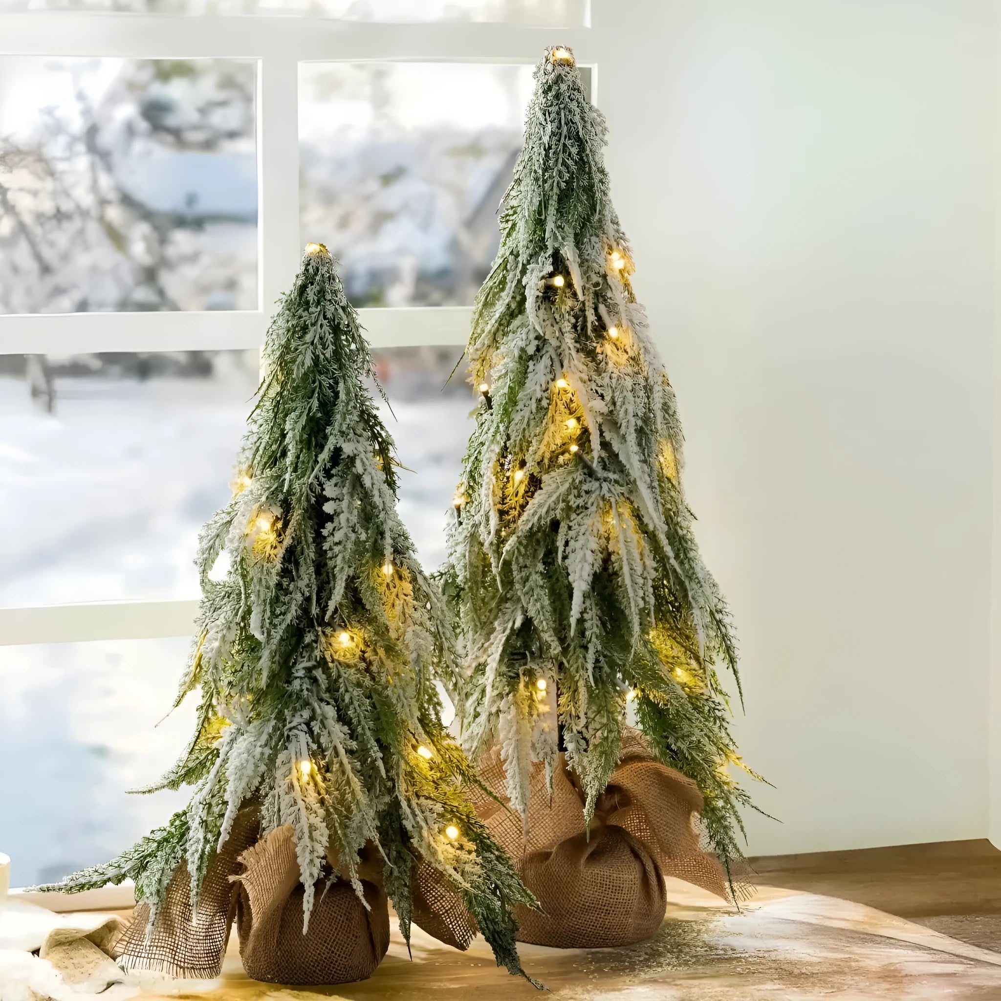 Small 24-inch artificial Christmas tree with white PE snow spray finish, green branches, built-in lights, and a red ornament