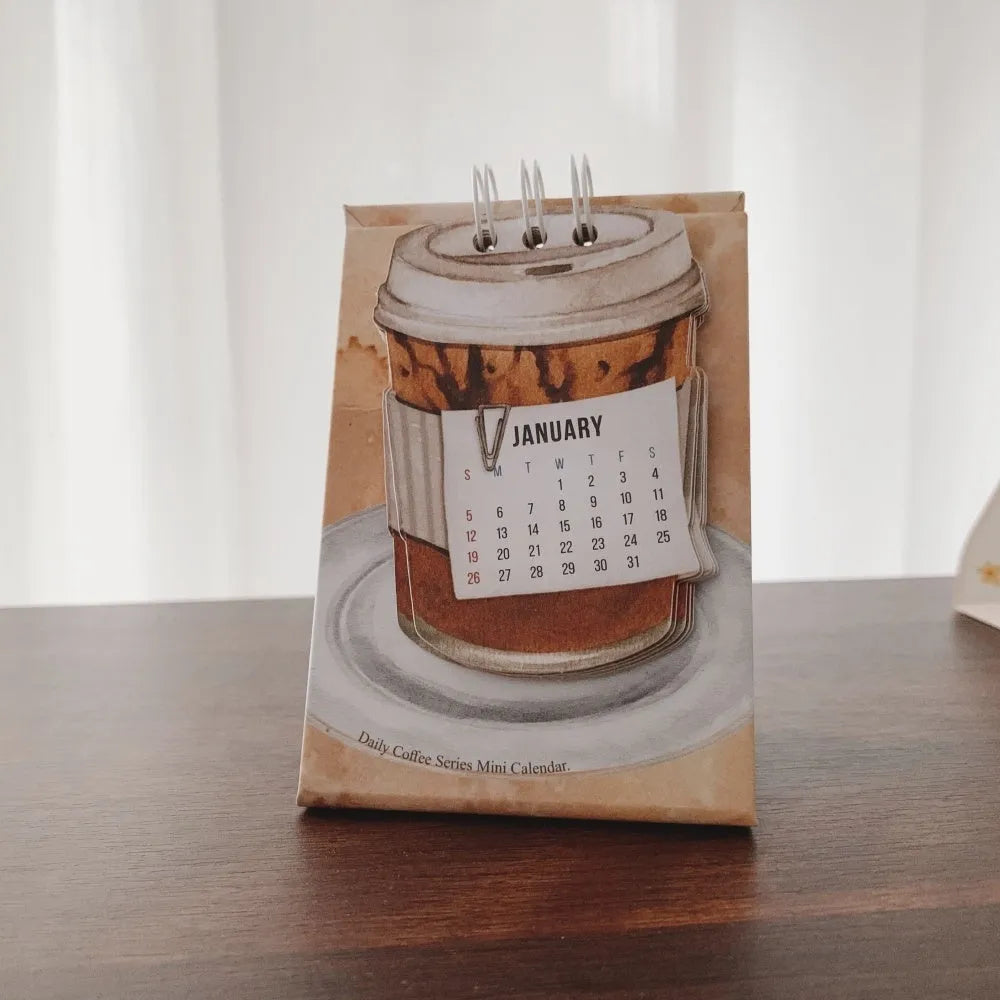 Set of four different 2025 mini paper desk calendars with simple modern designs on a desk.
