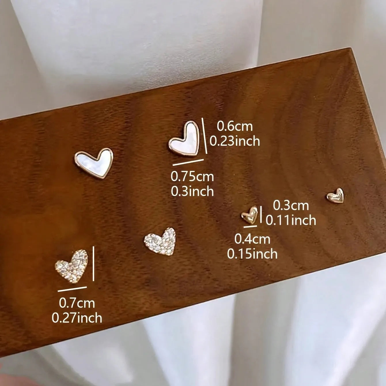 Three pairs of heart-shaped alloy earrings with electroplated finish in gold, black, black-white, and pink colours