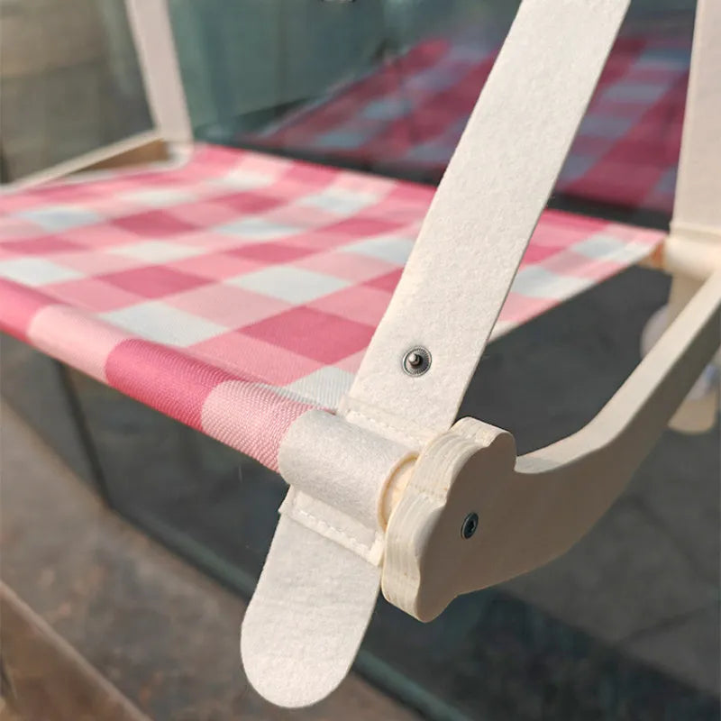 Pink wooden cat hammock bed with suction cups attached to a window
